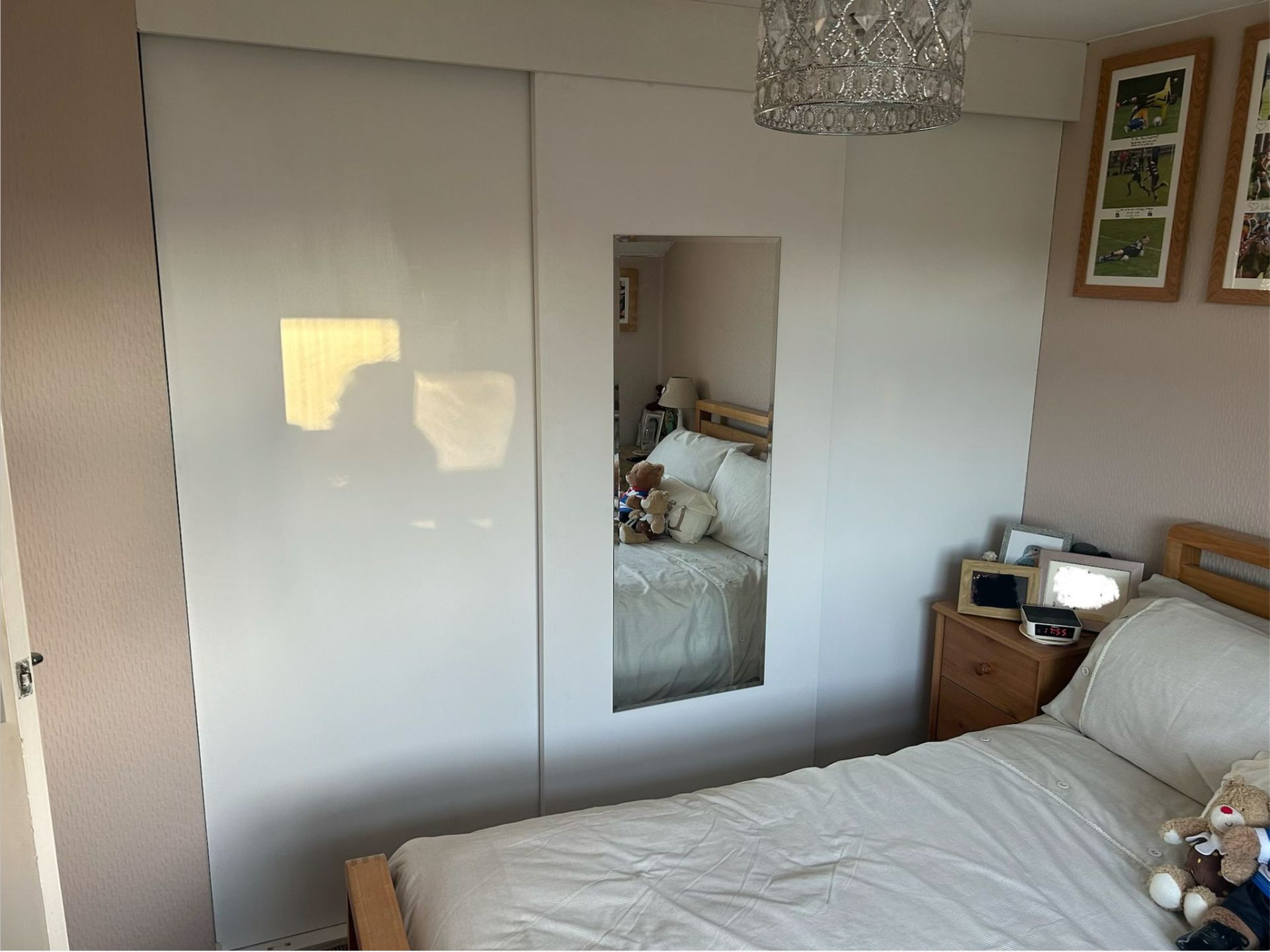 Fitted sliding wardrobe with mirrored doors installed in a Sidmouth bedroom by AJW Carpentry