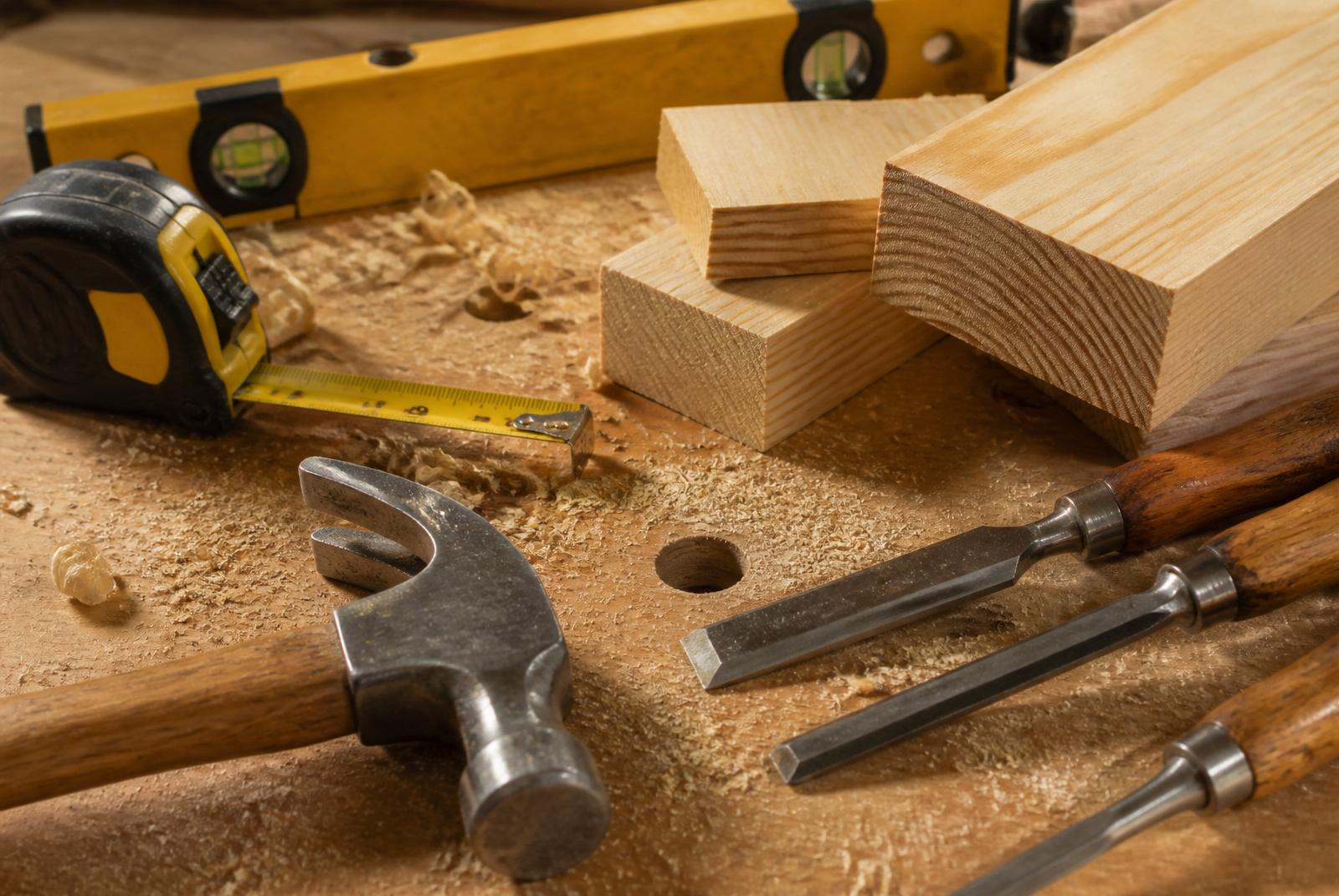 Carpentry tools, hammer, chisels, tape measure and spirit level, on a timber workbench